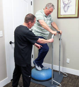 therapist helping patient on balance ball